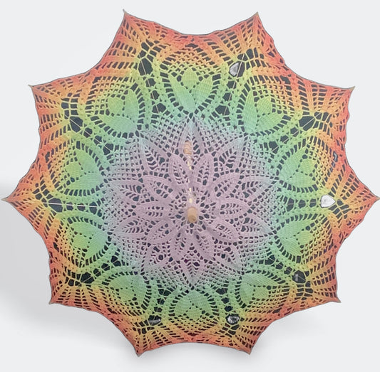 A parasol is open and facing the viewer. This is a self-drafted pattern and features the ROYGBIV rainbow for gaypride with pastel purple at the center and red at the edge.