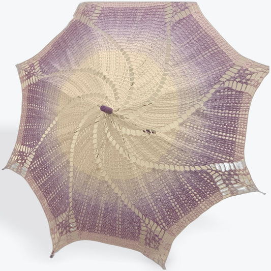 A parasol is open and facing left of the viewer. This broad shade-providing pattern is one of my own design. The purple plastic end cap and arm tips are also seen.